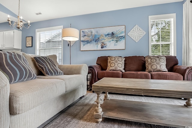 living room with a healthy amount of sunlight, dark wood-type flooring, and a chandelier