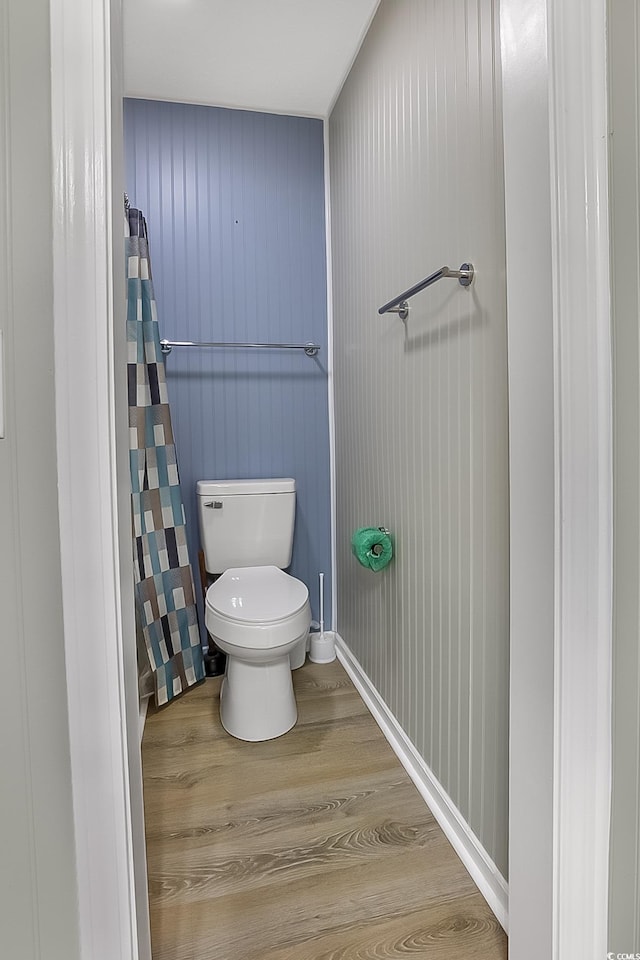 bathroom with wooden walls, toilet, and wood-type flooring