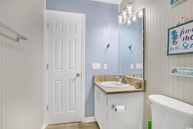 bathroom featuring vanity, wooden walls, hardwood / wood-style floors, and toilet