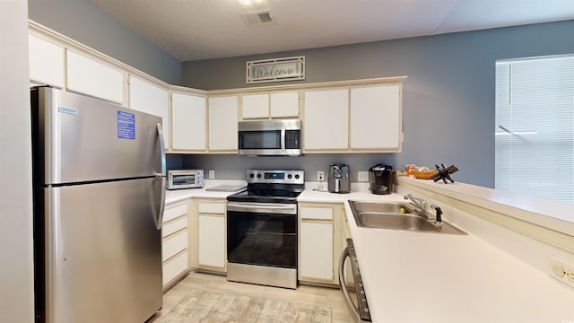 kitchen featuring white cabinetry, sink, light hardwood / wood-style flooring, and appliances with stainless steel finishes