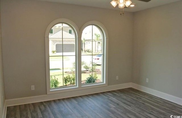 empty room with a wealth of natural light, ceiling fan, and dark hardwood / wood-style flooring