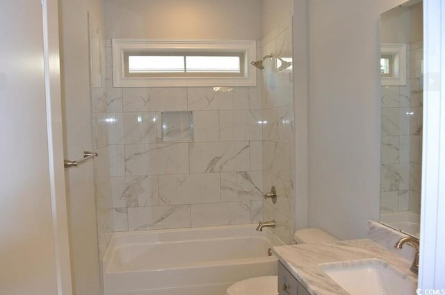 full bathroom featuring tiled shower / bath, vanity, and toilet