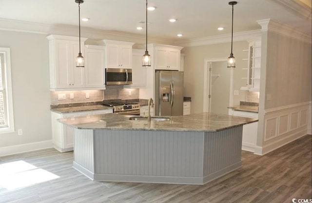 kitchen with hanging light fixtures, a kitchen island with sink, sink, and stainless steel appliances