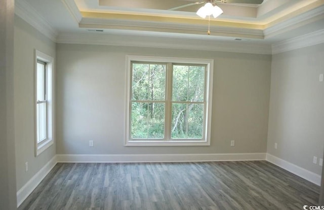 empty room with a tray ceiling, ornamental molding, dark hardwood / wood-style flooring, and a healthy amount of sunlight