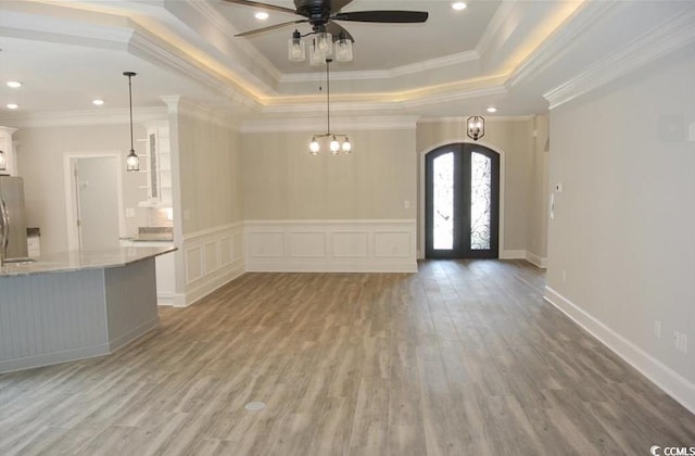 interior space with french doors, a raised ceiling, crown molding, and light hardwood / wood-style floors