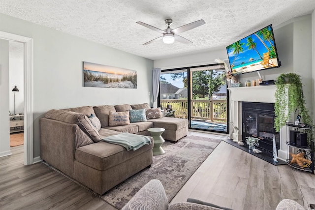 living room featuring hardwood / wood-style flooring, ceiling fan, and a textured ceiling