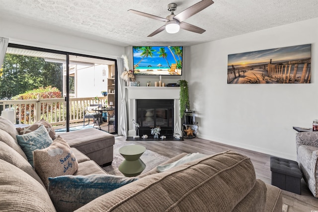 living room with ceiling fan, wood-type flooring, and a textured ceiling