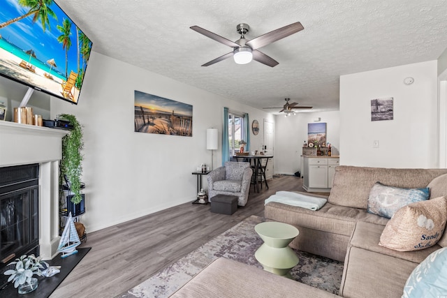 living room featuring ceiling fan, hardwood / wood-style floors, and a textured ceiling