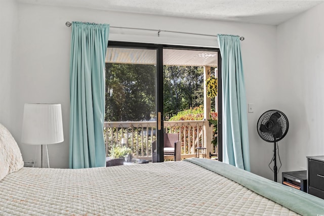 bedroom with access to outside, multiple windows, and a textured ceiling