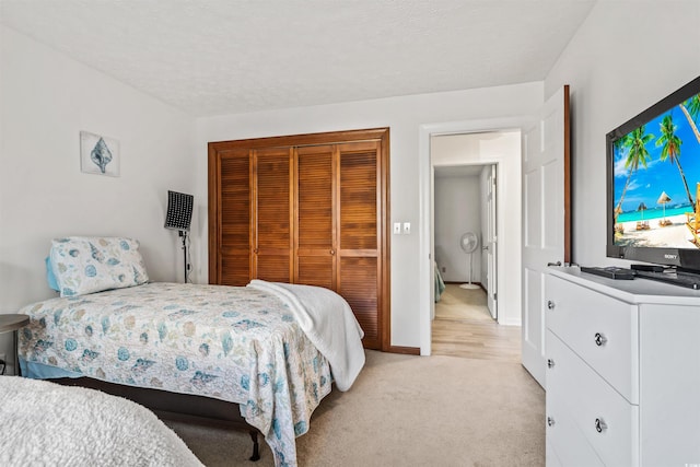 bedroom with a closet, light carpet, and a textured ceiling