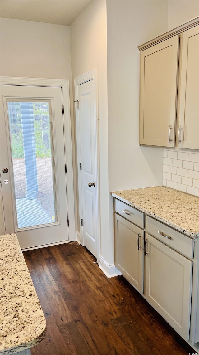 interior space with light stone countertops, decorative backsplash, and dark wood-type flooring