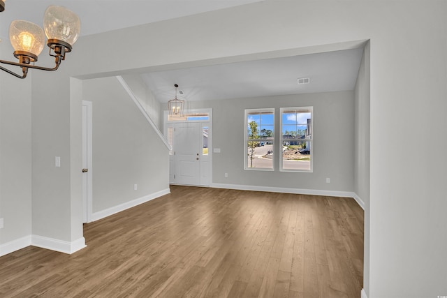 unfurnished living room featuring hardwood / wood-style floors and a chandelier