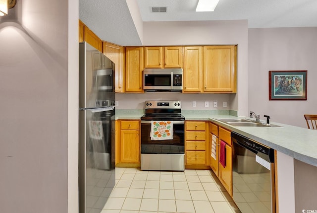 kitchen featuring light countertops, visible vents, appliances with stainless steel finishes, a sink, and a peninsula