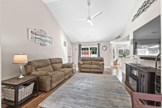 living room featuring vaulted ceiling, ceiling fan, dark hardwood / wood-style flooring, and a textured ceiling