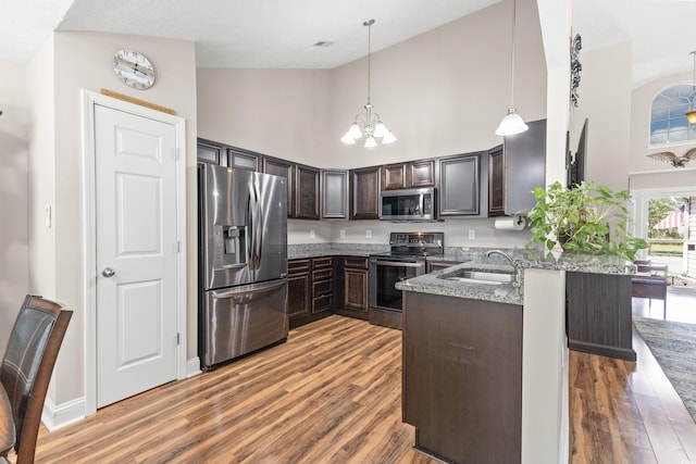 kitchen featuring pendant lighting, kitchen peninsula, sink, dark brown cabinetry, and stainless steel appliances