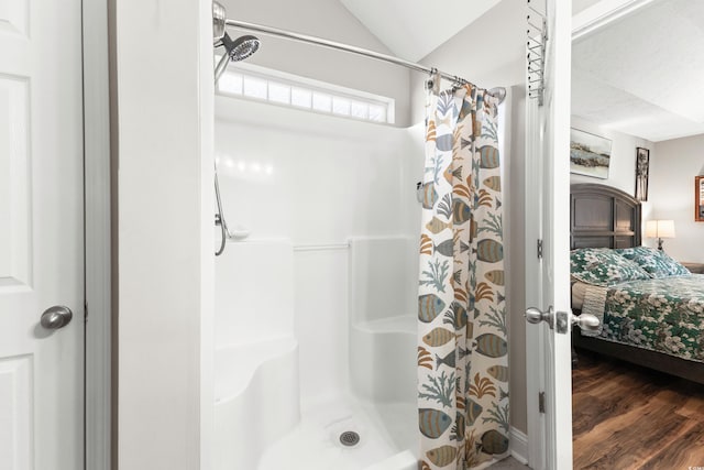 bathroom with wood-type flooring, walk in shower, and vaulted ceiling