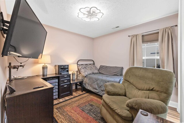 bedroom with a textured ceiling and light hardwood / wood-style flooring