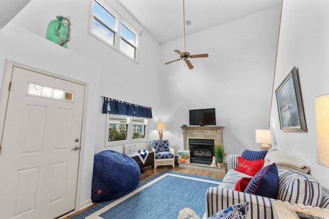 living room with ceiling fan, wood-type flooring, and a towering ceiling