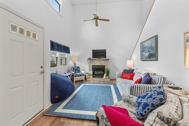 living room with a high ceiling, hardwood / wood-style flooring, and ceiling fan