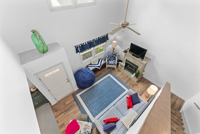 living room featuring ceiling fan, hardwood / wood-style floors, and a towering ceiling