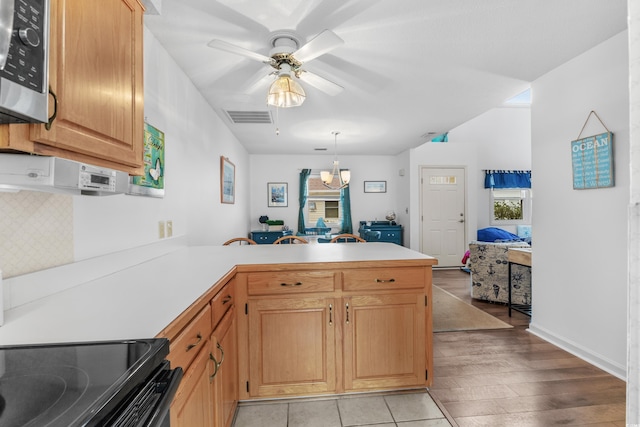 kitchen featuring kitchen peninsula, black range oven, decorative light fixtures, and ceiling fan with notable chandelier