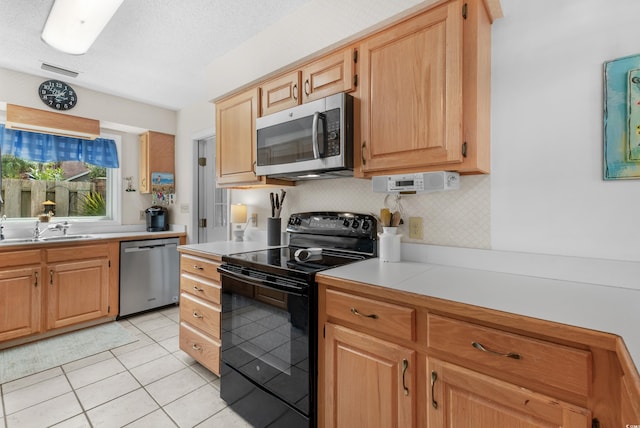 kitchen featuring sink, stainless steel appliances, tasteful backsplash, a textured ceiling, and light tile patterned floors