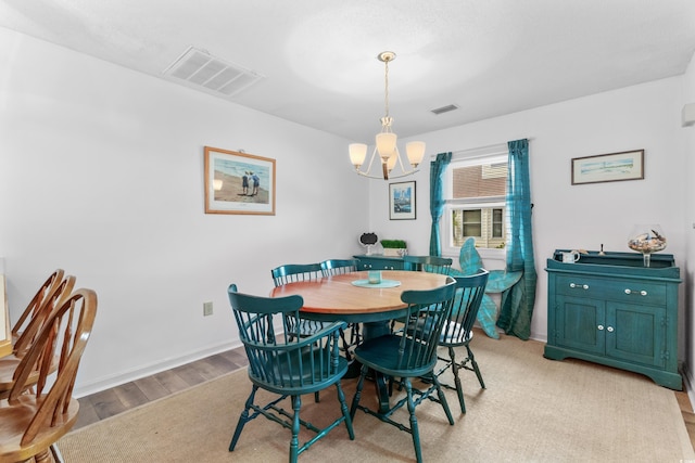 dining room with light hardwood / wood-style floors and a chandelier