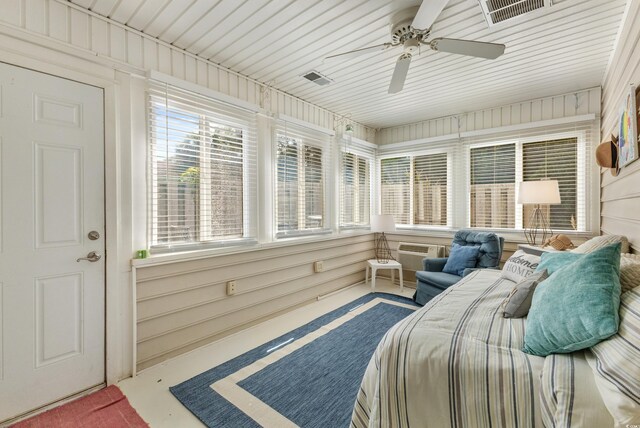 bedroom featuring multiple windows, concrete floors, ceiling fan, and wooden walls