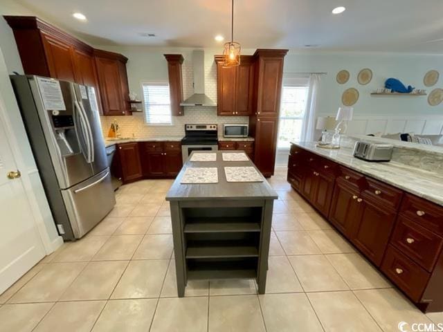 kitchen featuring hanging light fixtures, wall chimney range hood, stainless steel appliances, a center island, and decorative backsplash