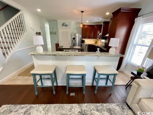 kitchen featuring light hardwood / wood-style flooring, plenty of natural light, hanging light fixtures, and stainless steel fridge