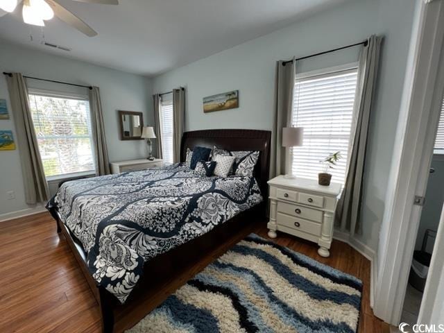 bedroom featuring ceiling fan, dark hardwood / wood-style flooring, and multiple windows