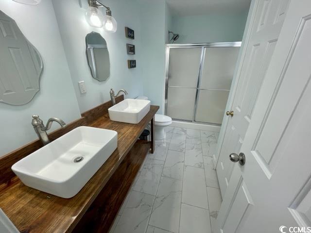 bathroom featuring vanity, toilet, and an enclosed shower