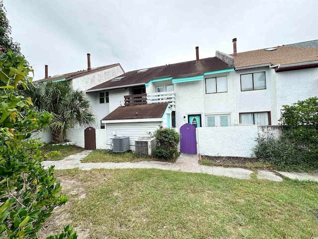 back of house with central air condition unit and a yard