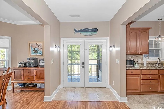 doorway to outside featuring light wood-type flooring, crown molding, sink, and french doors