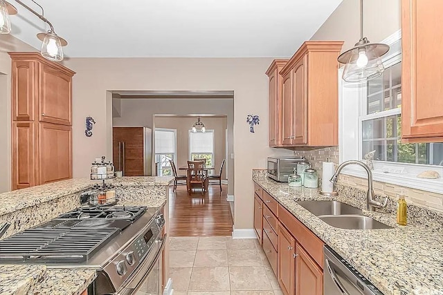 kitchen with pendant lighting, sink, light hardwood / wood-style flooring, appliances with stainless steel finishes, and decorative backsplash