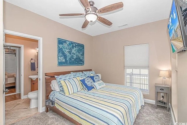 bedroom featuring connected bathroom, ceiling fan, and light colored carpet