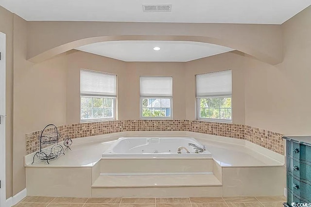 bathroom featuring a wealth of natural light, tile patterned flooring, and a tub