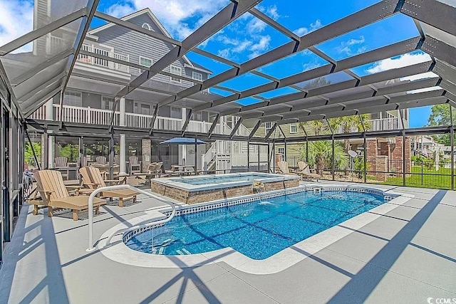 view of pool featuring glass enclosure, an in ground hot tub, and a patio area