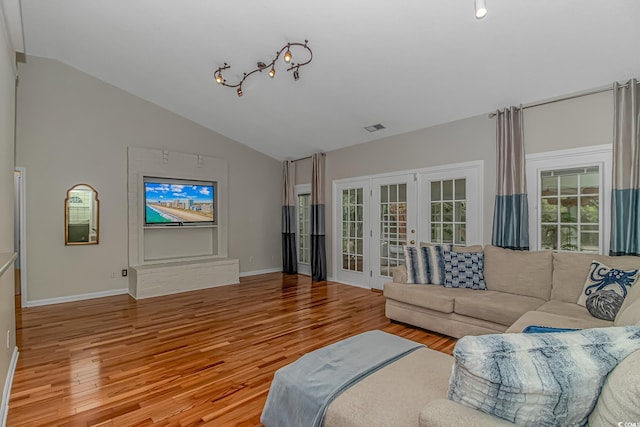 living room with french doors, light hardwood / wood-style flooring, and vaulted ceiling