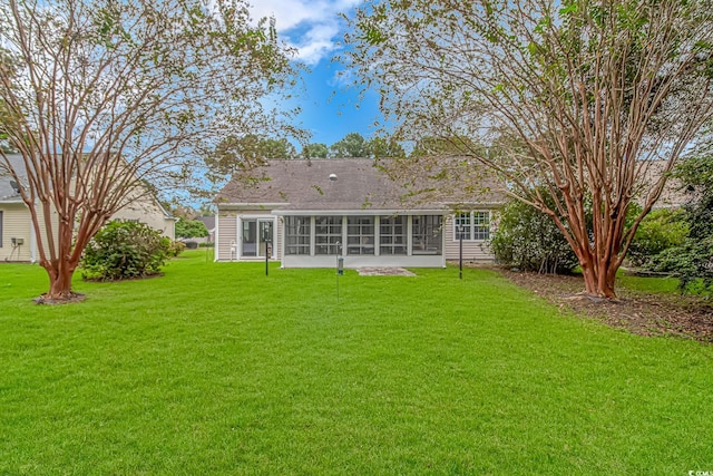 rear view of house featuring a yard and a sunroom