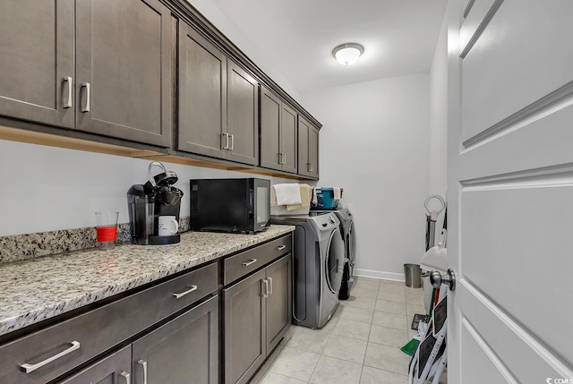 laundry area with cabinets, light tile patterned floors, and washer and clothes dryer