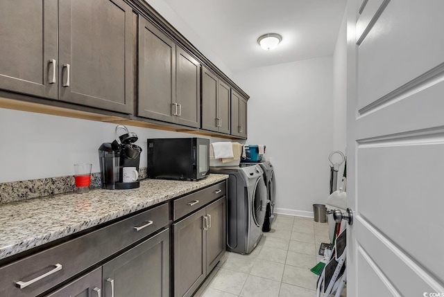laundry room featuring separate washer and dryer, cabinet space, light tile patterned flooring, and baseboards