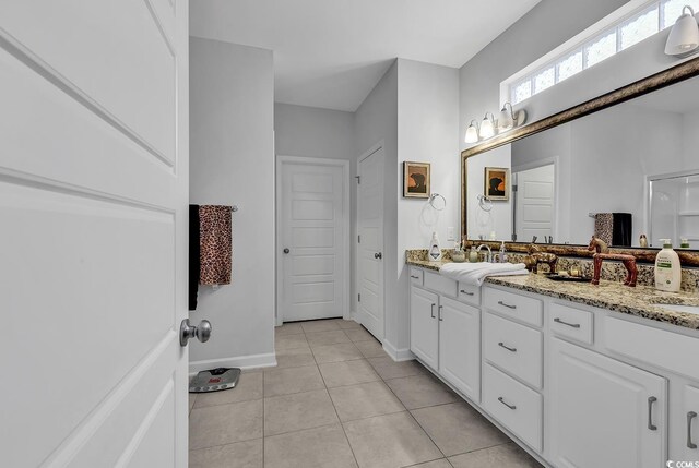 bathroom with baseboards, tile patterned flooring, and double vanity