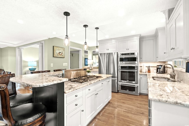 kitchen featuring white cabinetry, a center island, light hardwood / wood-style flooring, pendant lighting, and appliances with stainless steel finishes