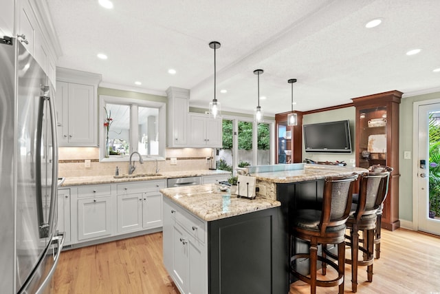 kitchen featuring a center island, white cabinetry, a healthy amount of sunlight, and appliances with stainless steel finishes