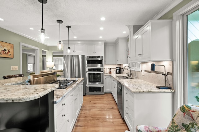 kitchen with white cabinets, appliances with stainless steel finishes, a textured ceiling, and hanging light fixtures