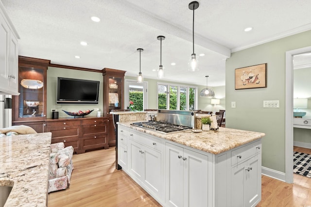 kitchen with pendant lighting, stainless steel gas stovetop, a textured ceiling, light hardwood / wood-style floors, and white cabinetry