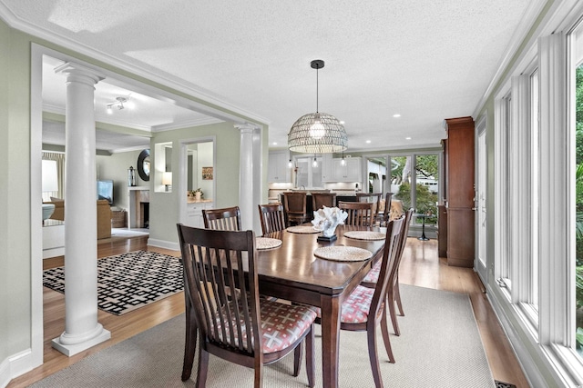 dining room with decorative columns, crown molding, light hardwood / wood-style flooring, and a textured ceiling