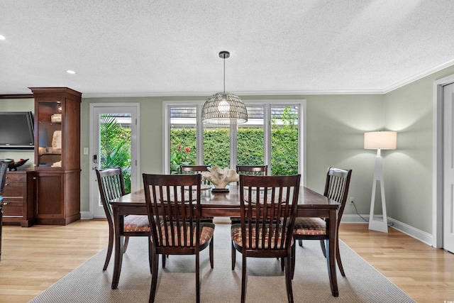 dining room with light hardwood / wood-style floors, ornamental molding, and a wealth of natural light