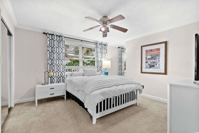 carpeted bedroom with a textured ceiling, a closet, ceiling fan, and crown molding